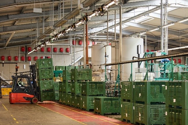 Ein Querverschiebewagen (Binmatic, vorne rechts) nimmt die Kisten mit den sortierten Äpfeln auf und stapelt sie auf der gegenüberliegenden Seite zur Abholung für die Staplerfahrer.